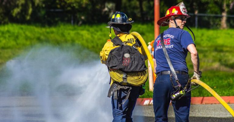 Helmets - Two firefighters are spraying water on a road