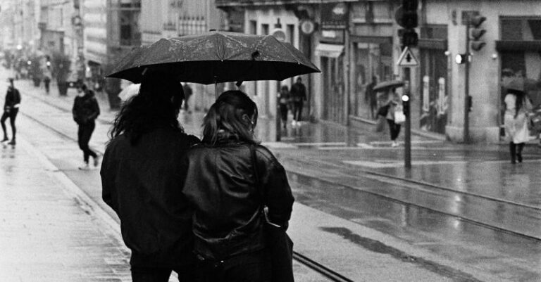 Sharing The Road - Backside of a Couple Sharing an Umbrella