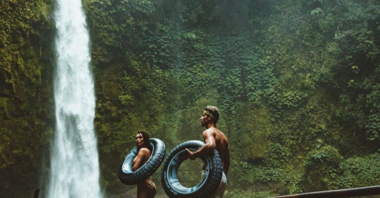 Adventures - Two Person Carrying Black Inflatable Pool Float on Brown Wooden Bridge Near Waterfalls